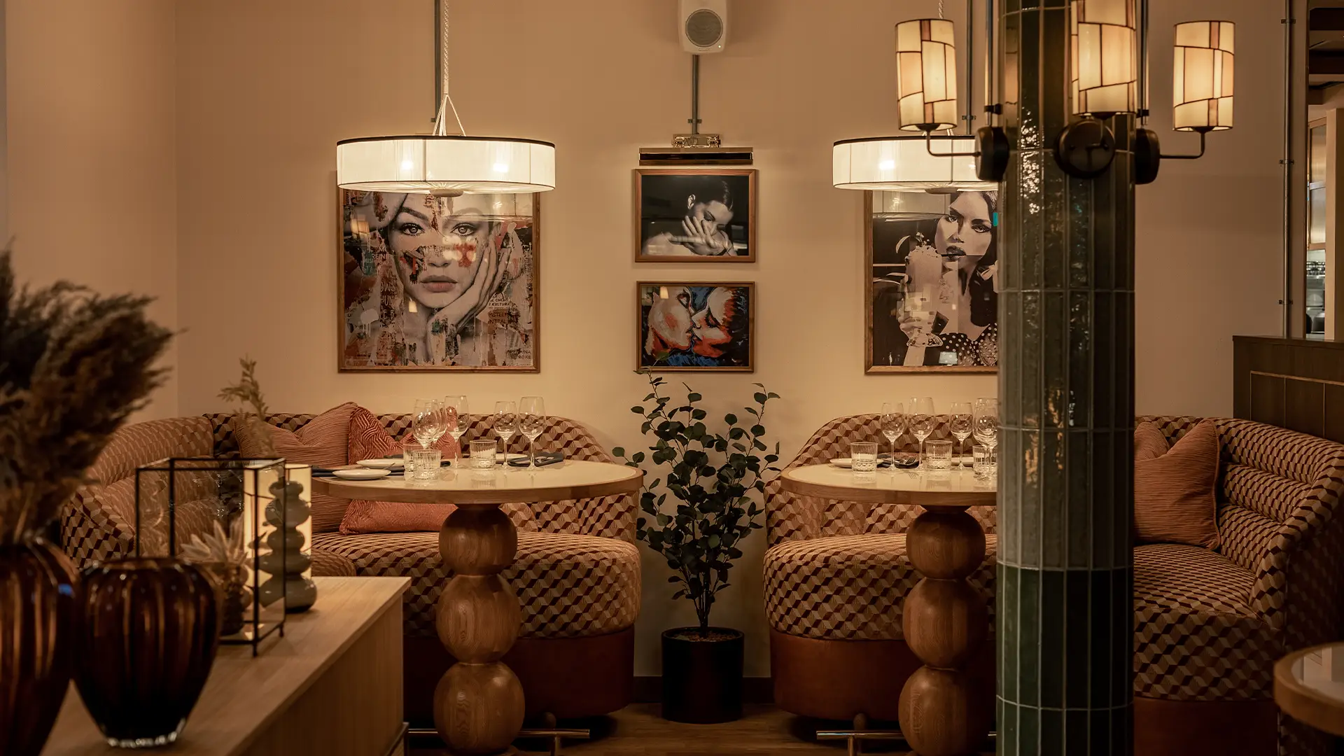 Archies-mysig-restaurang-goteborg Två intima middagsbord i mjuk belysning med konst på väggarna och dova färgtoner.