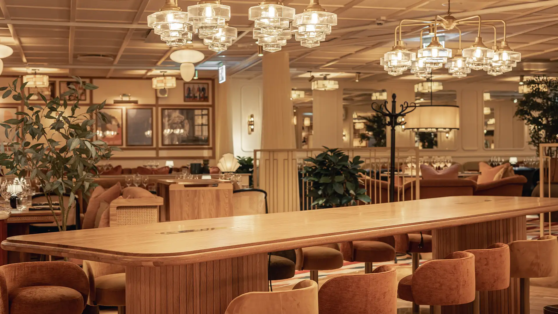 archies-restaurang-med-stort-bord Ett långt träbord med stoppade stolar i varm miljö hos Archie's restaurang.