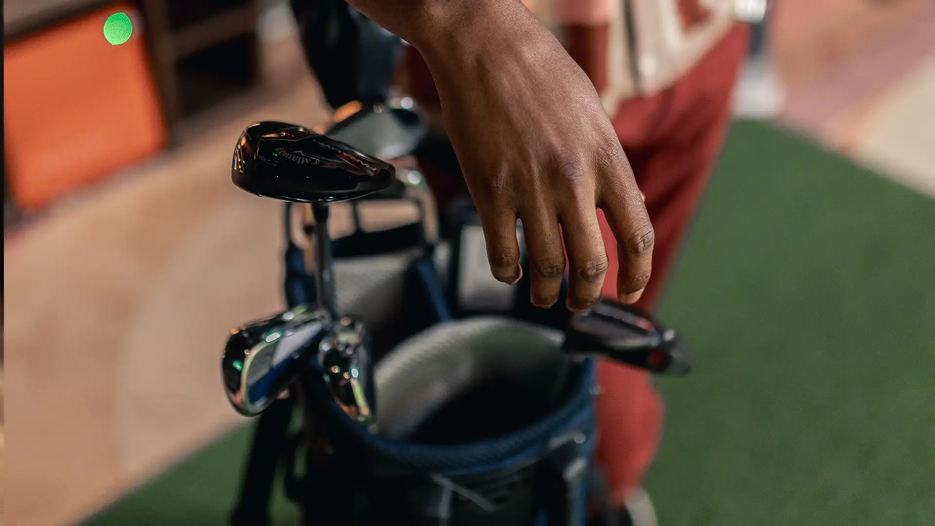 golf-simulator-i-stan En hand greppar en golfklubba ur en golfbag.