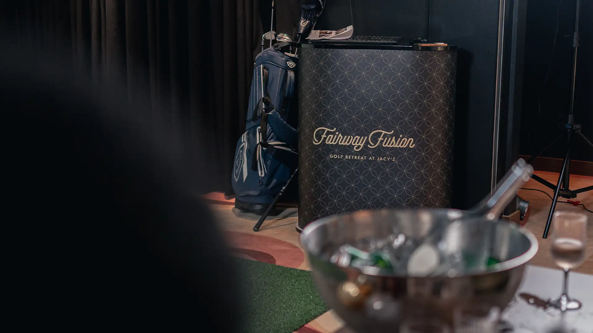 golf-simulator-jacyz Fairway Fusion-golfsimulatorn på Jacy’z med golfbag och dryckesbord i förgrunden.