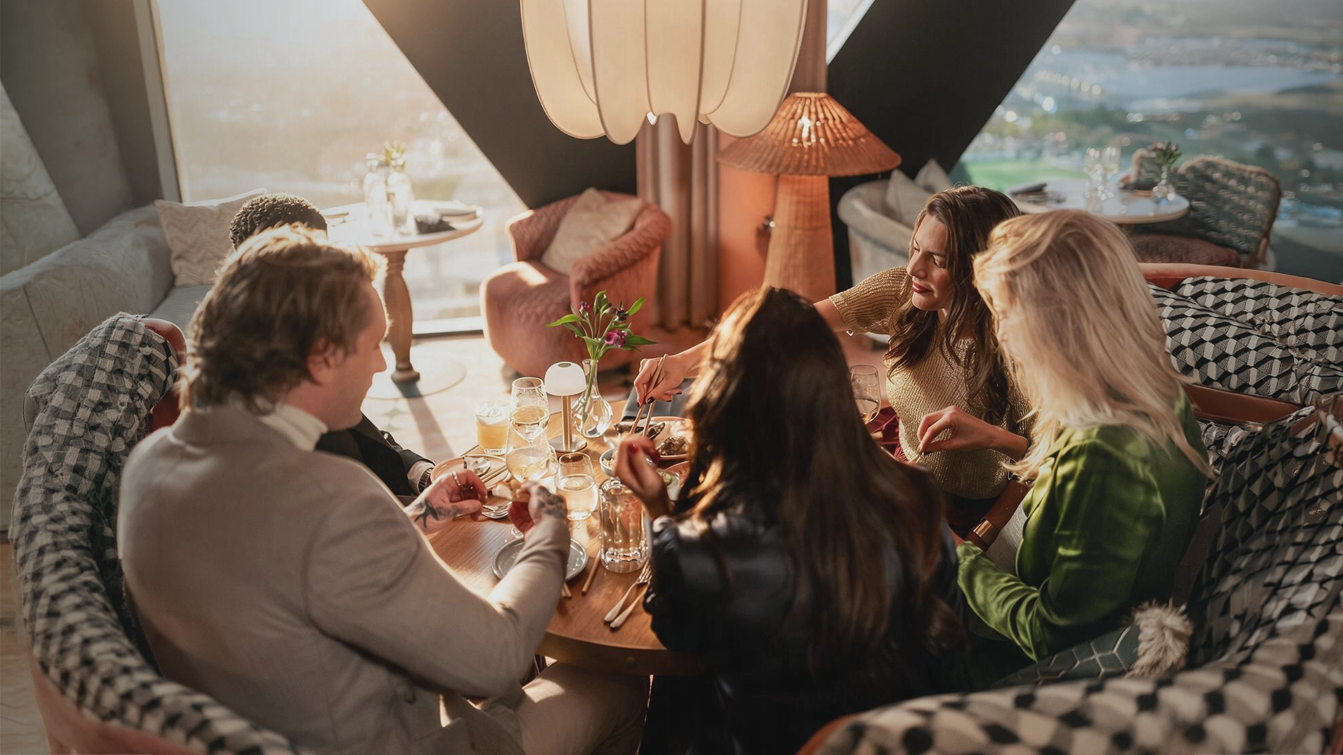 brunch_asiatisk_goteborg Sällskap runt ett dukat bord som äter asiatisk mat vid stora fönster med utsikt över Göteborg.